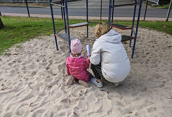 Mutter und Tochter suchen im Sand