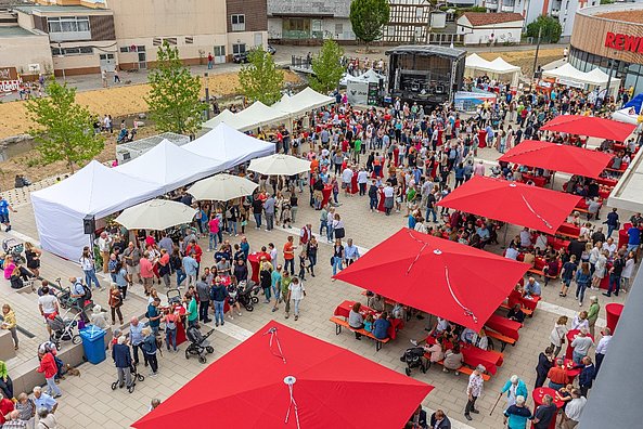 Blick von oben auf rote Schirme und viele BesucherInnen beim Familienfest auf dem Stadtplatz